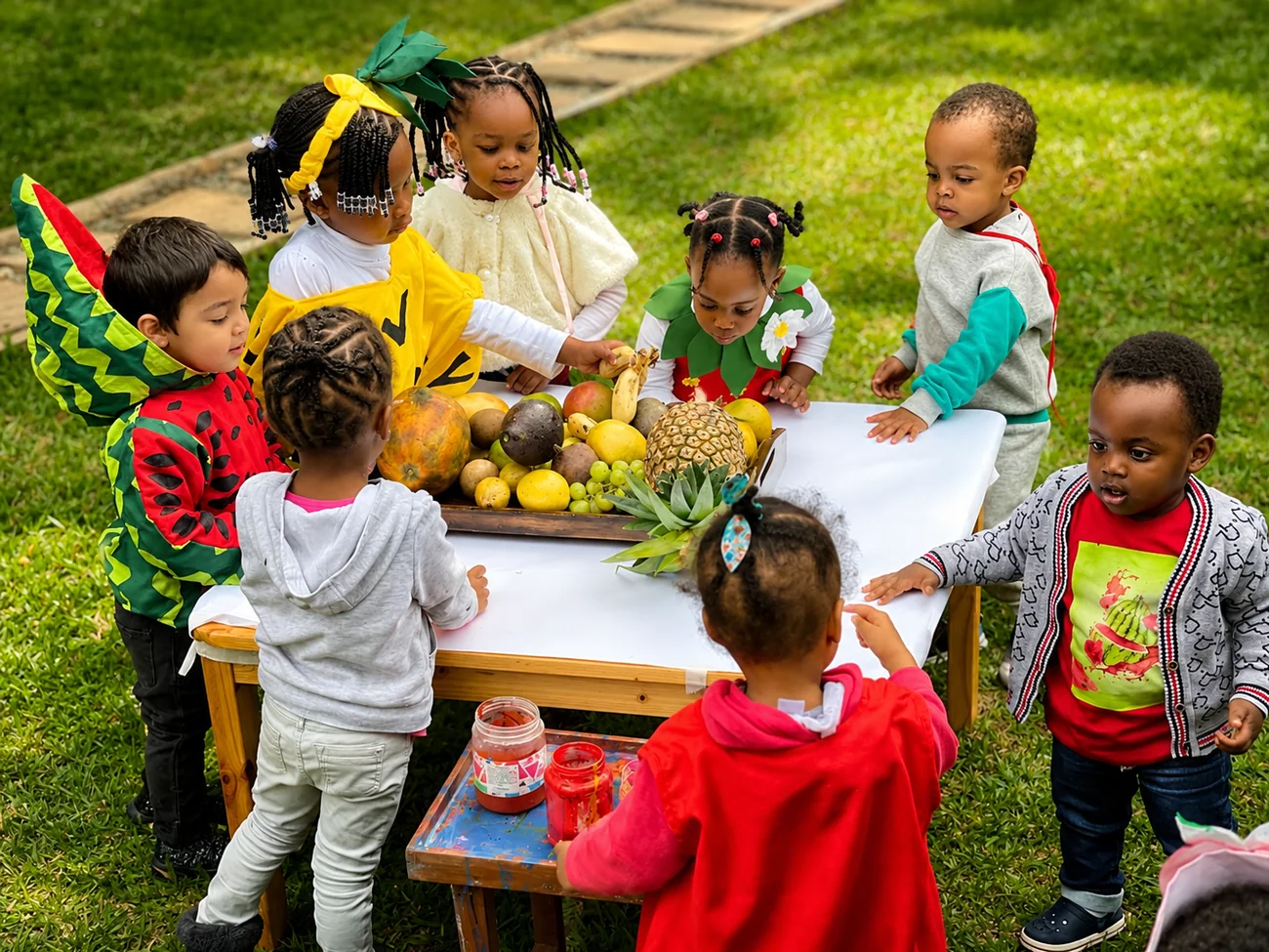 Children exploring fresh fruit and painting outdoors at The Little Nest